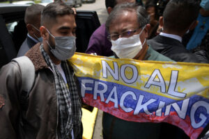 Colombian President Gustavo Petro holds a banner showing that he opposes fracking for natural gas, reflecting questions about his oil and gas and green energy policies.