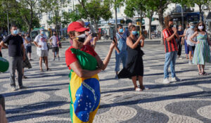 Woman wrapped in a Brazilian flag and red shirt and cap at a political rally in Portugal in 2020.