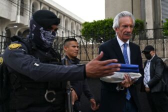 Guatemalan journalist is escorted after a legal hearing, reflecting crack downs on journalists and other anti-corruption investigators, including judges and government prosecutors.