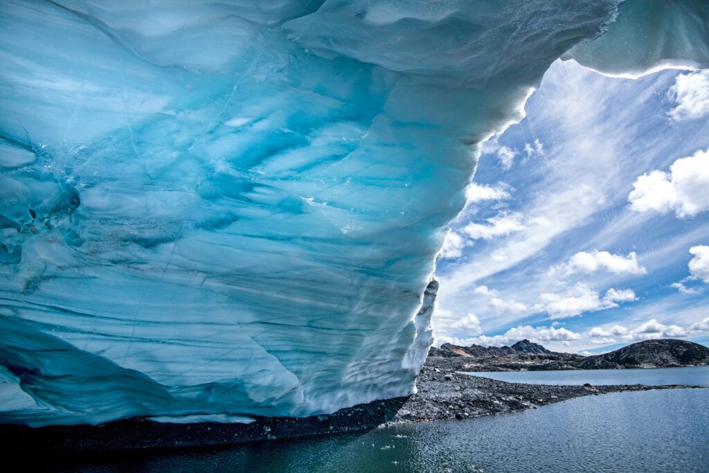 An ice cave at 16,000 feet above sea level, photographed in 2021, extends over Pastoruri Glacier Lake in the Cordillera Blanca range of the Andes. The giant cave has since disappeared.