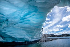 An ice cave at 16,000 feet above sea level, photographed in 2021, extends over Pastoruri Glacier Lake in the Cordillera Blanca range of the Andes. The giant cave has since disappeared.