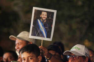 An image of President Nayib Bukele of El Salvador is raised during a national address on June 1 in San Salvador. Can liberal democracy adapt before it unravels? The global embrace of illiberal democrats reveals not just widespread disillusionment, but elite failure.