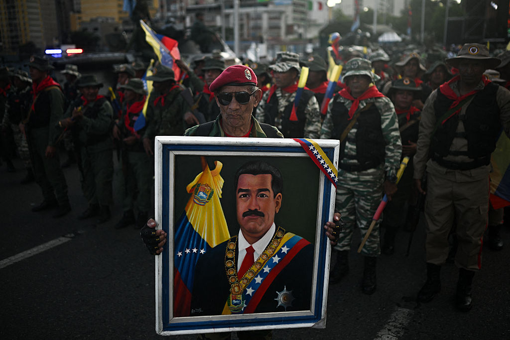 A member of the Bolivarian militia holds a picture of Nicolas Maduro during a military rally in Caracas on September 23, 2025.