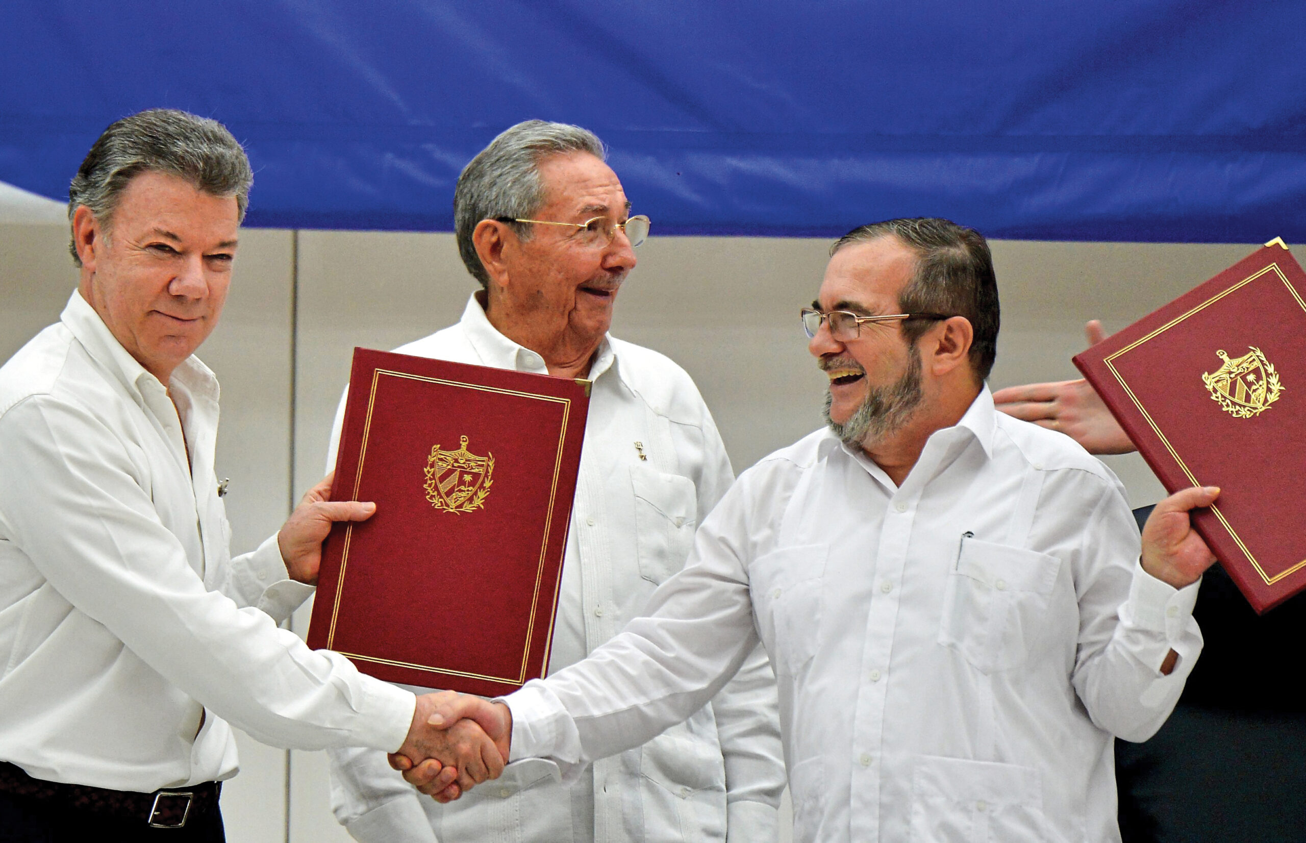 Colombia’s President Juan Manuel Santos (left) and Timoleón Jiménez, known as “Timochenko” (right), the FARC’s leader, shake hands in Cartagena in 2016 before the Peace Accord was finalized. Cuba’s President Raúl Castro (center) accompanied them.