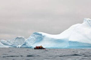 People take photos of an iceberg near the coast of Spert Island in Antarctica in December 2025.