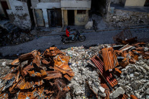 A motorcyclist drives by houses destroyed by armed gangs in 2024 in Port-au-Prince, Haiti in March 2026