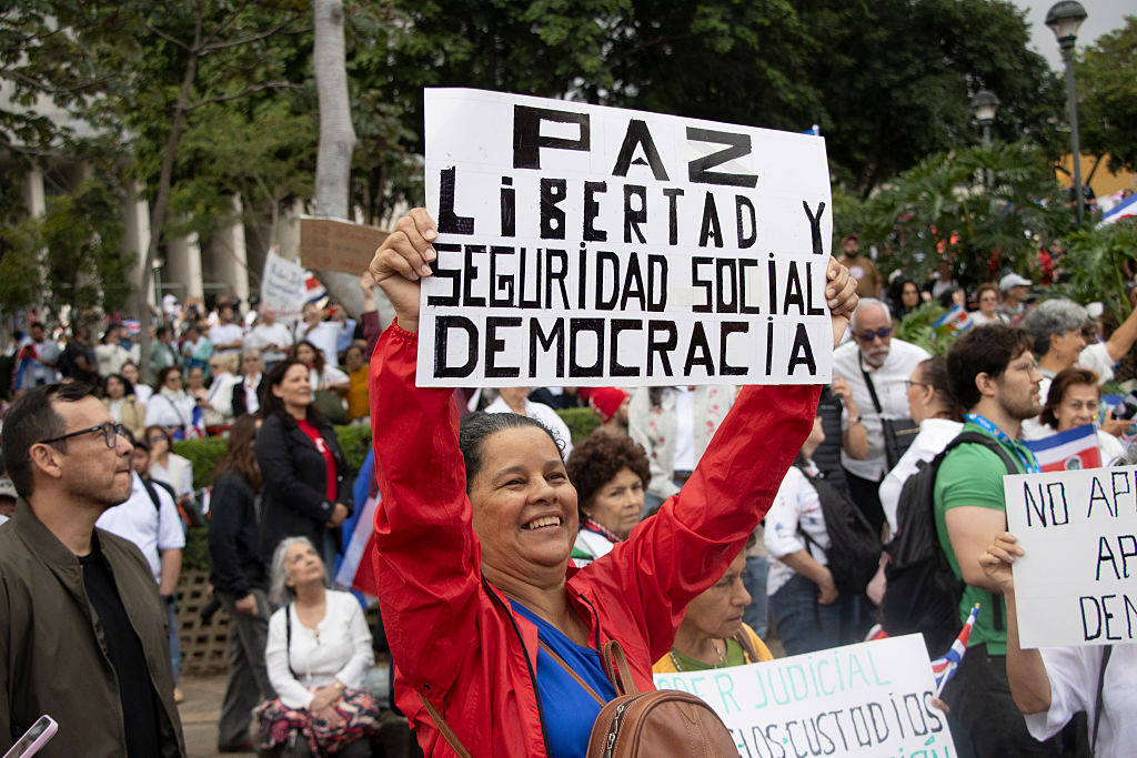 A protester in San José, Costa Rica, holds a sign expressing one definition of democracy in August.